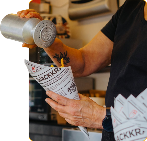 Medewerker van De Snackcar kruidt verse frietjes in een mobiele frituur.